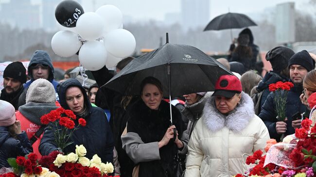 Люди возлагают цветы к стихийному мемориалу возле подмосковного Крокус Сити Холла в память о жертвах теракта