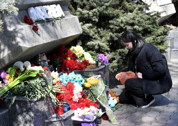 Девушка кладет мягкие игрушки к стихийному мемориалу в Комсомольском парке в Севастополе во время акции в память о жертвах теракта в подмосковном Крокус Сити Холле
