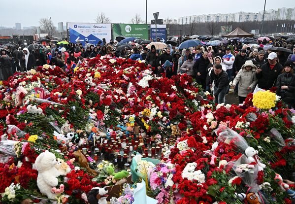 Люди возлагают цветы к стихийному мемориалу возле подмосковного Крокус Сити Холла в память о жертвах теракта