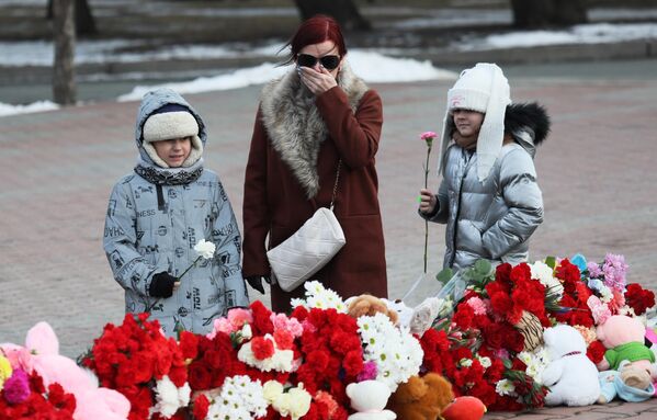 Женщина с девочками у стихийного мемориала на Красной площади в Красноярске в день общенационального траура по погибшим в результате теракта в подмосковном Крокус Сити Холле