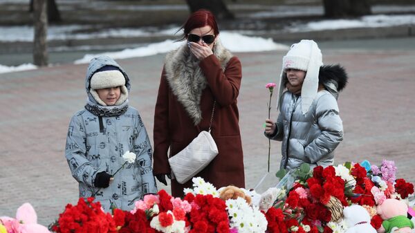 Женщина с девочками у стихийного мемориала на Красной площади в Красноярске в день общенационального траура по погибшим в результате теракта в подмосковном Крокус Сити Холле10