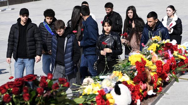 Молодые люди возлагают цветы к стихийному мемориалу на площади Ленина в Симферополе во время акции в память о жертвах теракта в подмосковном Крокус Сити Холле13