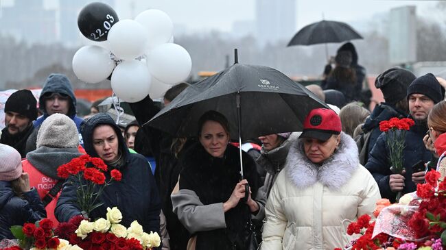 Люди возлагают цветы к стихийному мемориалу возле подмосковного Крокус Сити Холла в память о жертвах теракта