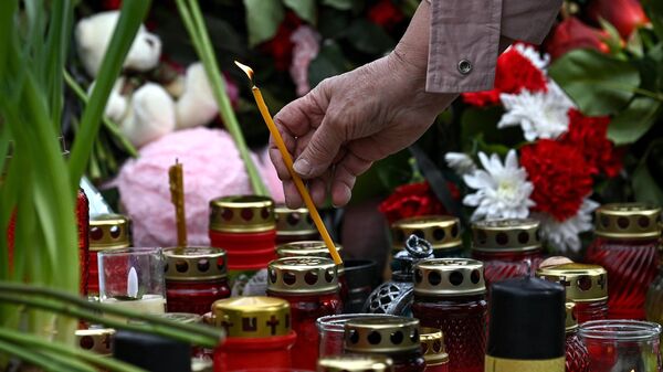 Женщина ставит свечку на стихийном мемориале у здания концертного зала Крокус Сити Холл, где произошел теракт