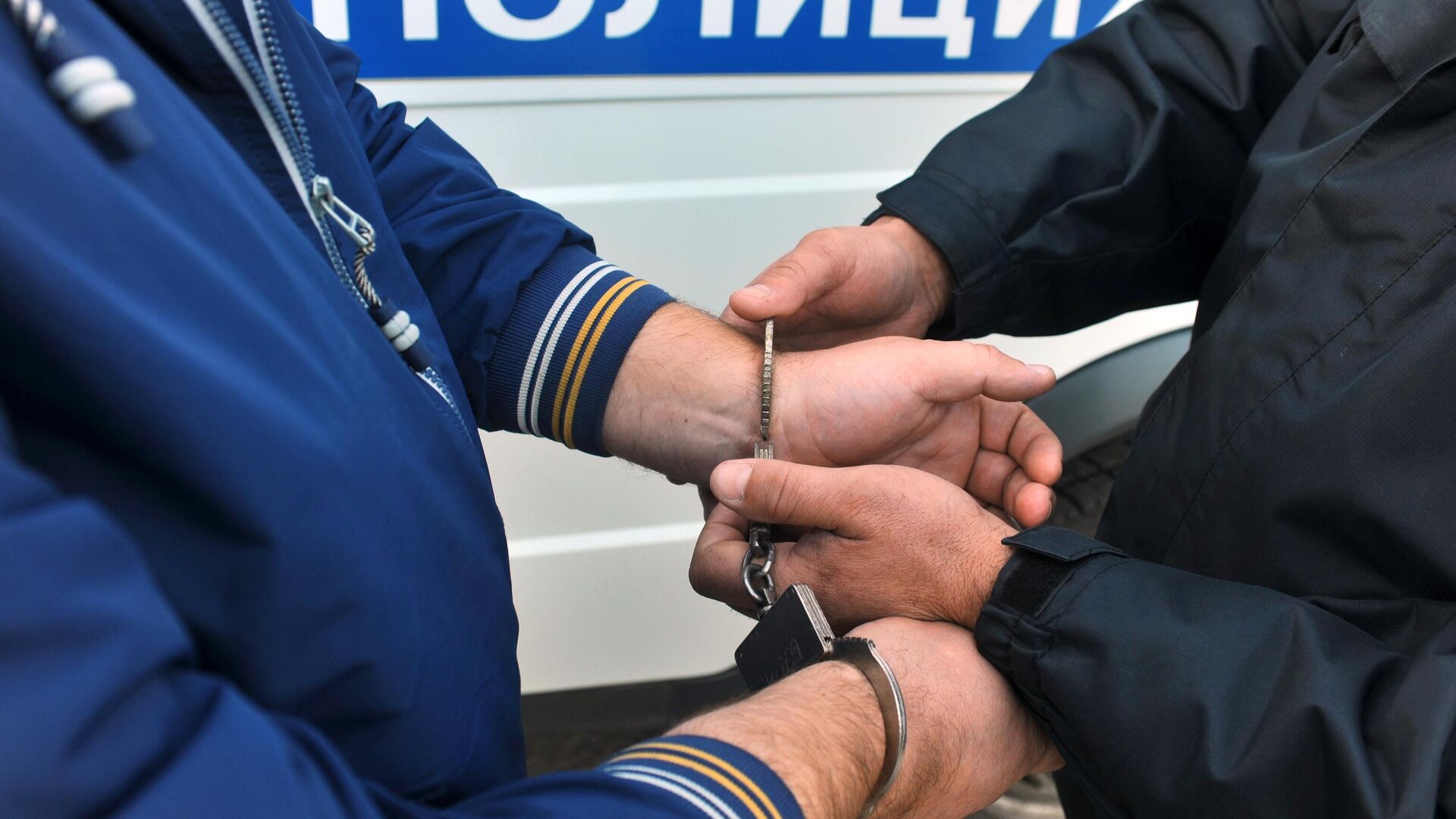 Сотрудник полиции УМВД надевает наручники на правонарушителя0