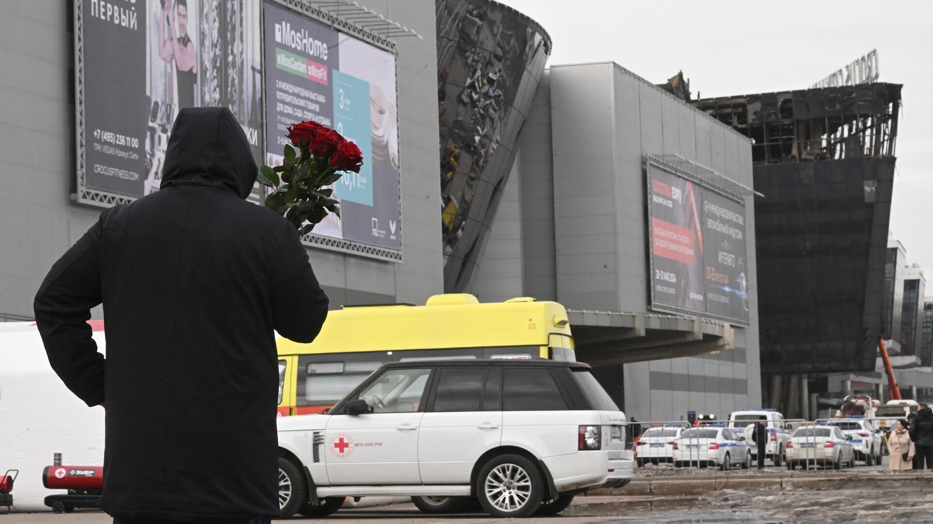 Мужчина с цветами у здания концертного зала Крокус Сити Холл, где произошел теракт0