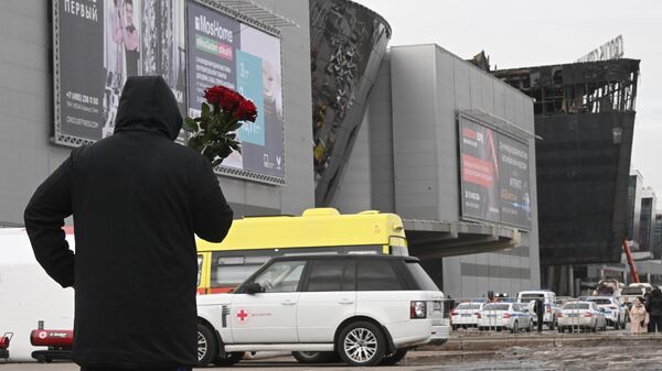 Мужчина с цветами у здания концертного зала Крокус Сити Холл, где произошел теракт