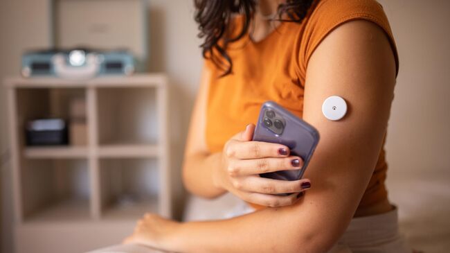 Девушка измеряет сахар крови при помощи Flash мониторинга глюкозы