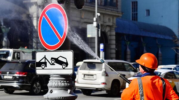 Сотрудник коммунальной службы моет дорожный знак на Тверской улице в Москве