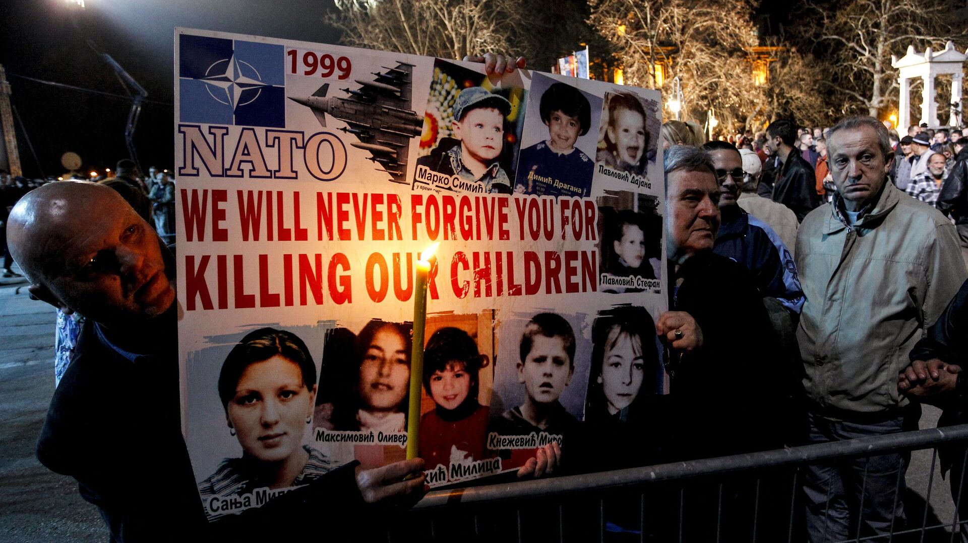 Сербские мужчины держат плакат с фотографиями жертв воздушной атаки НАТО в 1999 году - РИА Новости, 1920, 28.03.2024