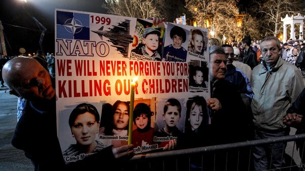 Сербские мужчины держат плакат с фотографиями жертв воздушной атаки НАТО в 1999 году
