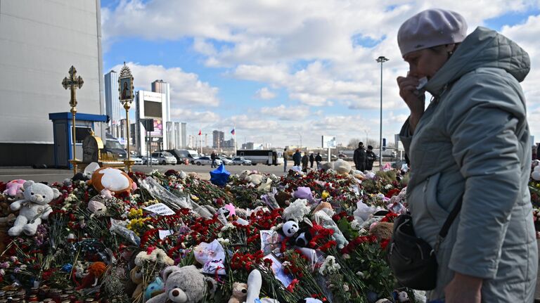 Женщина плачет у стихийного мемориала в память о жертвах теракта 22 марта 2024 г. в Крокус Сити Холле