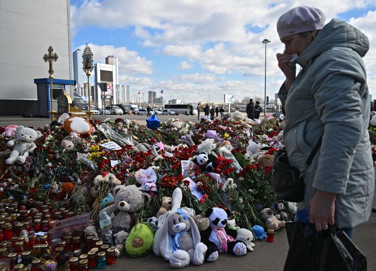 Женщина плачет у стихийного мемориала в память о жертвах теракта 22 марта 2024 г. в Крокус Сити Холле