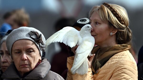 Женщина держит белого голубя во время заупокойной литии о жертвах теракта 22 марта 2024 г. в Крокус Сити Холле