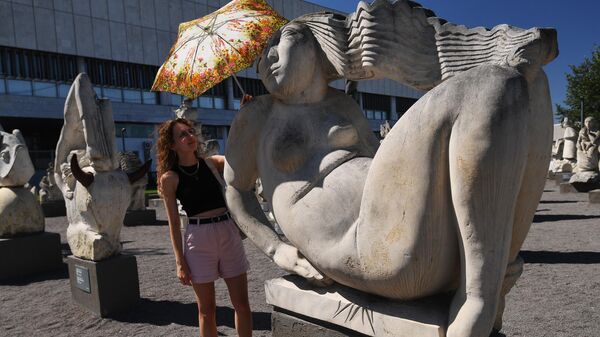 Девушка держит зонт над скульптурой