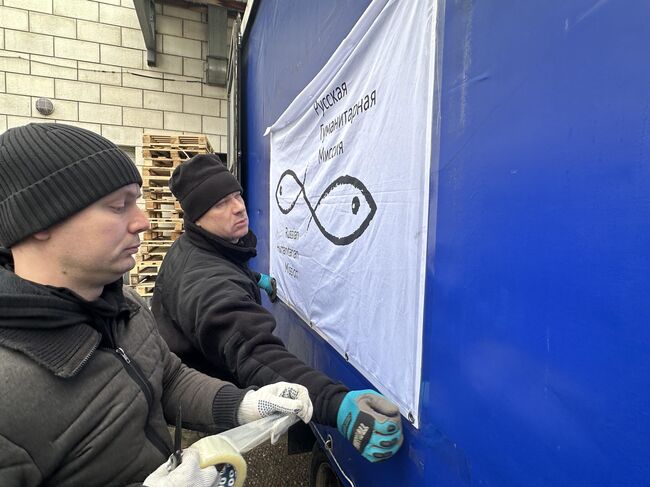 Сотрудники РГМ клеют флаг организации на борт грузовой газели