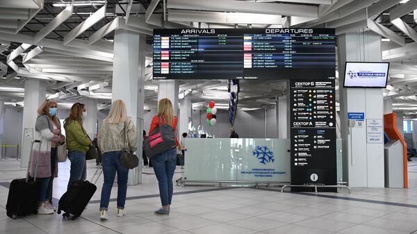 Пассажиры у информационного табло в аэропорту  