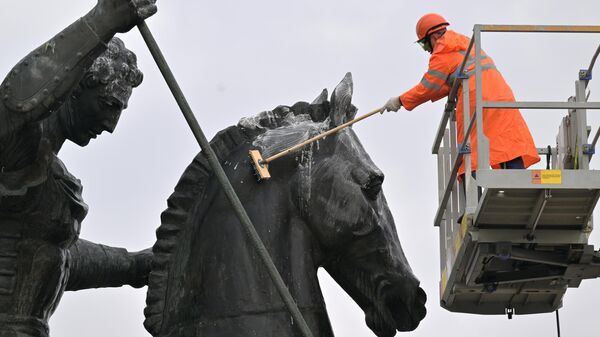 Сотрудник коммунальной службы промывает памятник Георгию Победоносцу на Поклонной горе в Москве