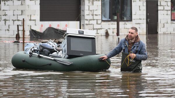 Житель вывозит технику на лодке из затопленного дома в ТСН Ивановское под Оренбургом