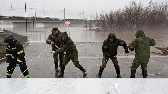 Сотрудники МЧС и военнослужащие устанавливают водоналивную дамбу, доставленную сегодня в Оренбург