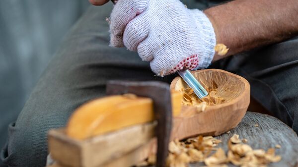 Мужчина изготавливает деревянную ложку