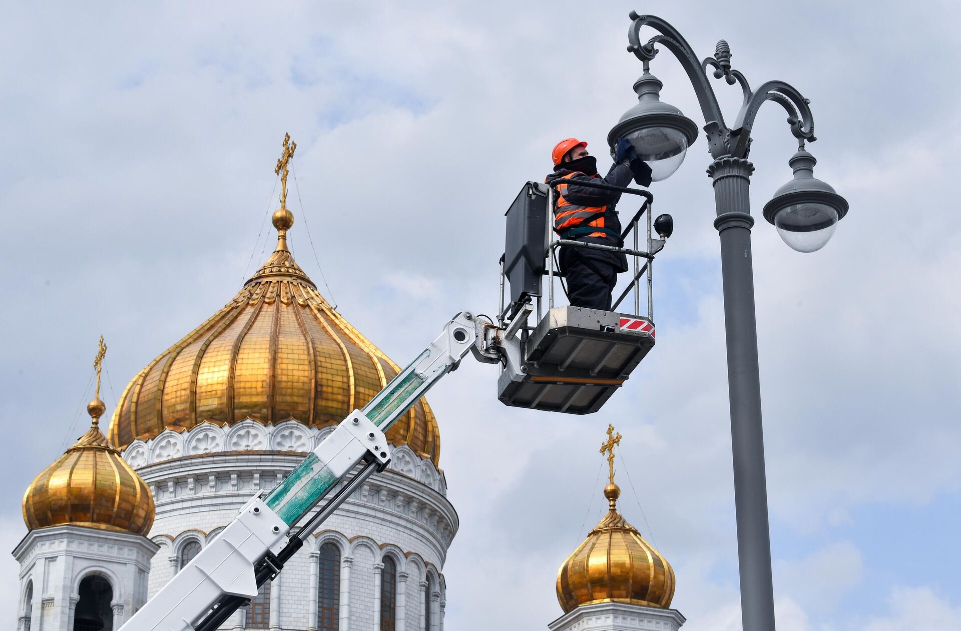 Сотрудник коммунальной службы протирает плафон фонаря наружного освещения на Пречистенской набережной в Москве - РИА Новости, 1920, 12.04.2024