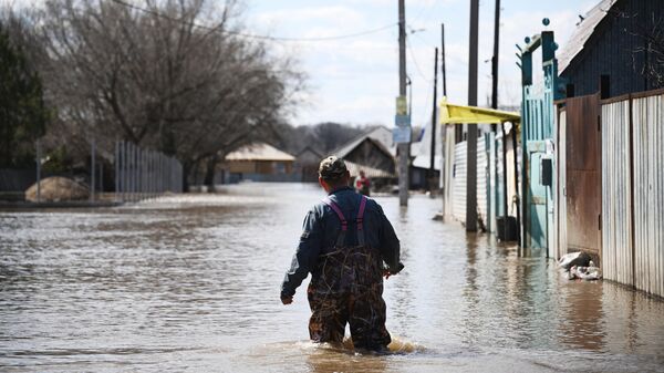 Мужчина идет по одной из затопленных улиц в Овчинном городке в Оренбурге