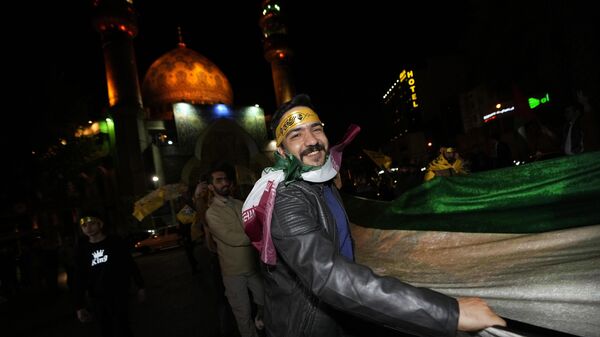 Демонстранты несут полотно в цветах иранского флага во время демонстрации в поддержку ночной атаки со стороны Ирана на Израиль. 14 апреля 2024