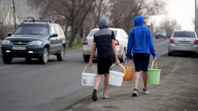 Подростки несут ведра с водой в Орске