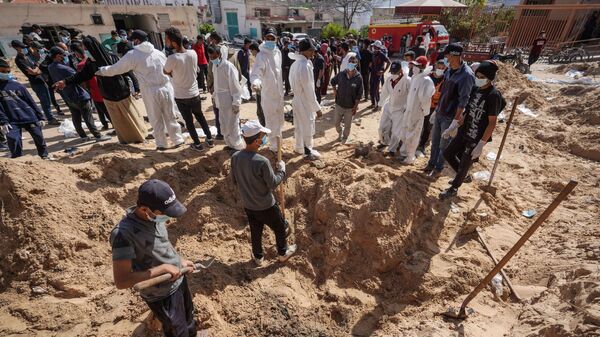 Палестинские работники здравоохранения раскапывают тела, похороненные израильскими войсками на территории больницы Насера в Хан-Юнисе на юге сектора Газа