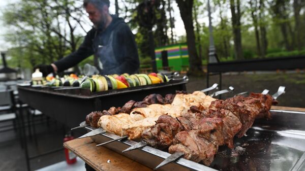 Мужчина готовит овощи на гриле на фестивале фудтраков в парке Сокольники в Москве