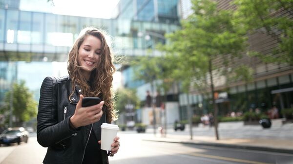 Девушка смотрит на экран смартфона на улице