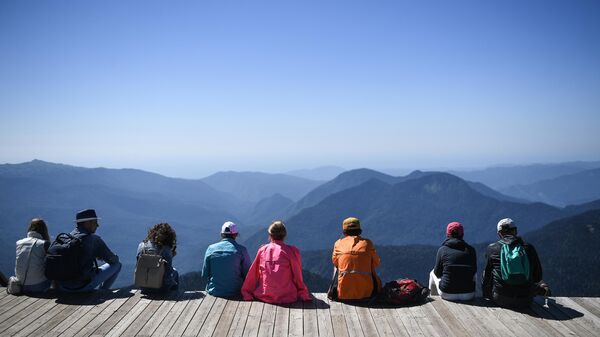 Туристы на обзорной площадке на вершине Роза Пик на высоте 2320 метров на горном курорте Роза Хутор в Красной Поляне