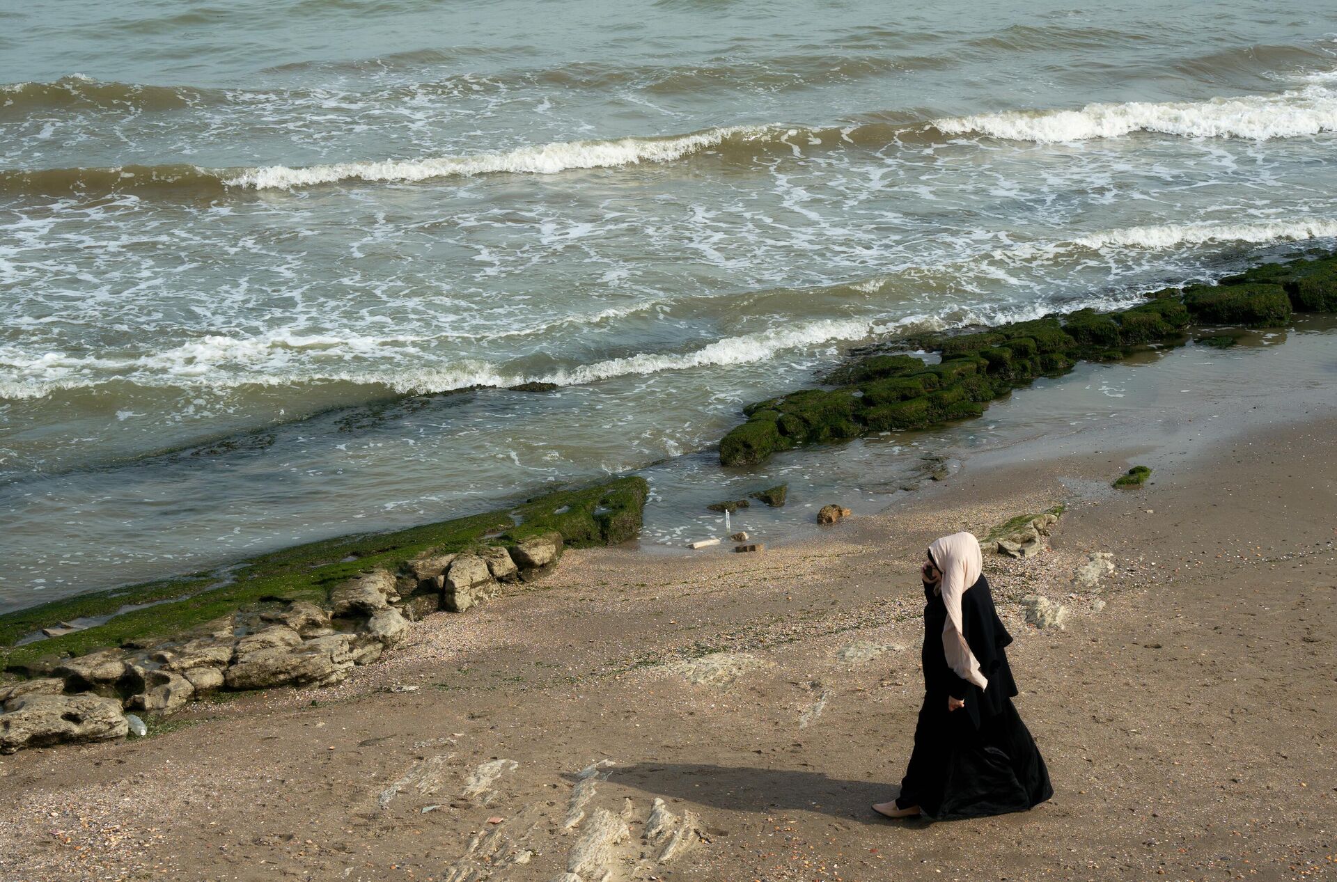 Женщина разговаривает по телефону на берегу Каспийского моря в Махачкале - РИА Новости, 1920, 03.05.2024