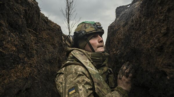 Украинский военнослужащий укрывается в окопе