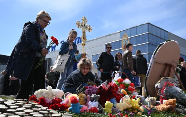 Люди у стихийного мемориала возле подмосковного Крокус Сити Холла в память о жертвах теракта 22 марта 2024 г.
