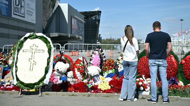 Молодые люди у стихийного мемориала возле подмосковного Крокус Сити Холла в память о жертвах теракта 22 марта 2024