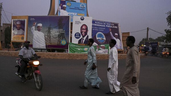 Люди на фоне предвыборных плакатов кандидатов в президенты Чада