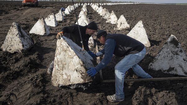 Рабочие устанавливают зубы драконаи недалеко от границы с Россией в Харьковской области