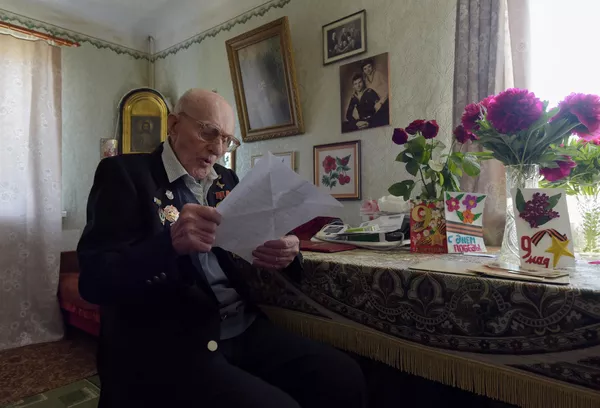 大祖国戦争の退役軍人ニコライ・イワノビッチ・デニセンコがドネツクのキーロフスキー地区の自宅でボランティアからの手紙を読む