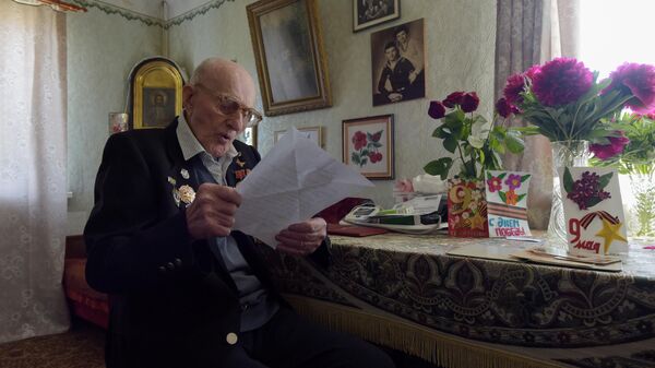 Ветеран Великой Отечественной войны Николай Иванович Денисенко читает письмо от волонтера в своем доме в Кировском районе Донецка