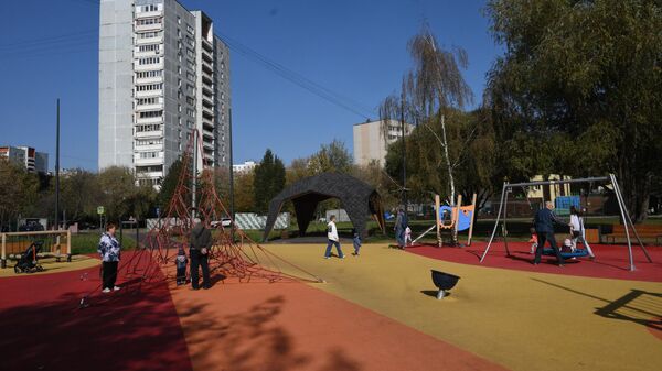 Люди с детьми гуляют на детской площадке в парке Яуза