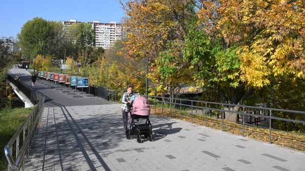 Женщина с коляской гуляет в парке Яуза