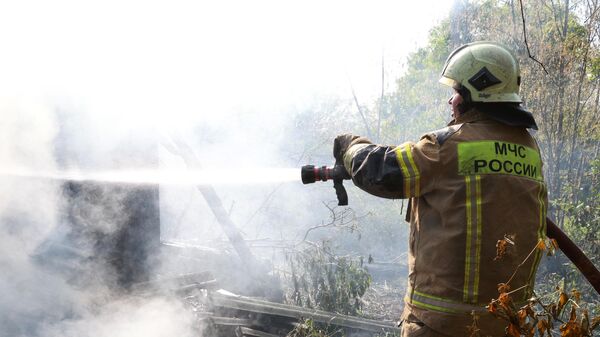 Сотрудник пожарной службы МЧС РФ тушит пожар в жилом доме, возникший в результате обстрела со стороны ВСУ города Моспино
