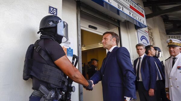 Президент Франции Эммануэль Макрон пожимает руку полицейскому в центральном полицейском участке в Нумеа, Новая Каледония. 23 мая 2024