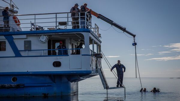 Дайверы крепят найденный затонувший якорь к крану-манипулятору научно исследовательского судна Анастасия для подъема