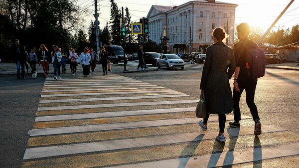 Прохожие переходят дорогу на закате в Архангельске