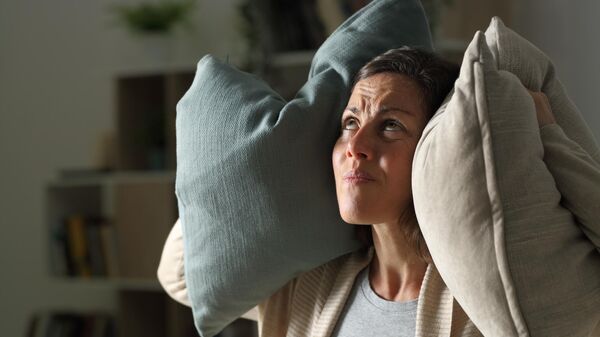 Женщина закрывает уши подушками. Архивное фото 
