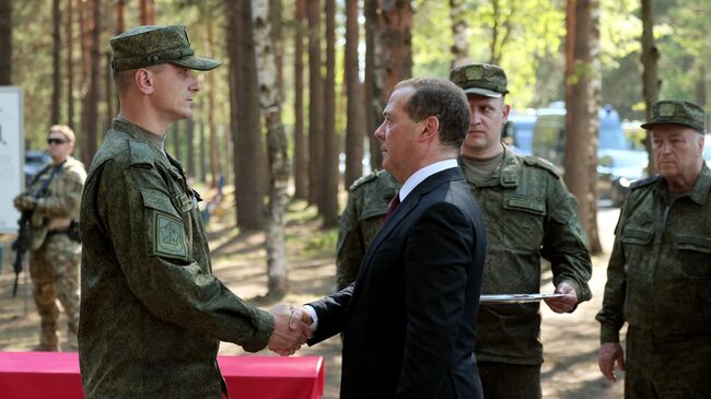 Заместитель председателя Совета безопасности РФ Дмитрий Медведев награждает государственными наградами военнослужащих ВС РФ во время посещения полигона Песочненский в Ленинградской области