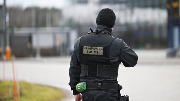 Финский пограничник стоит на границе между Россией и Финляндией на пограничном пункте Нуйямаа